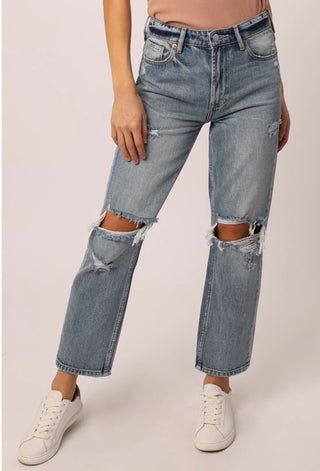 A pair of faded blue high-rise ankle jeans with a ripped hem.