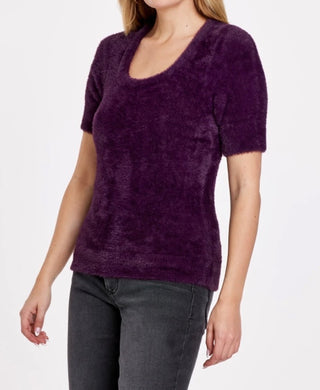 A woman wearing a royal purple, long-sleeved, round-necked top.