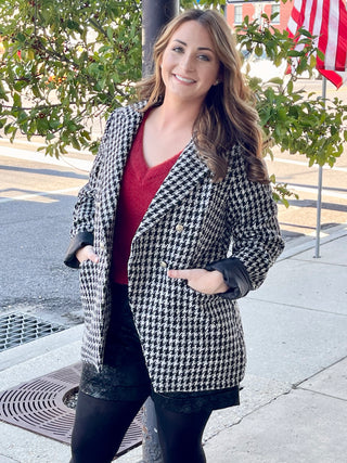 A houndstooth, black blazer and paired with a fuzzy red, V-neck top and Black snake skin Textured shorts with black stockings underneath