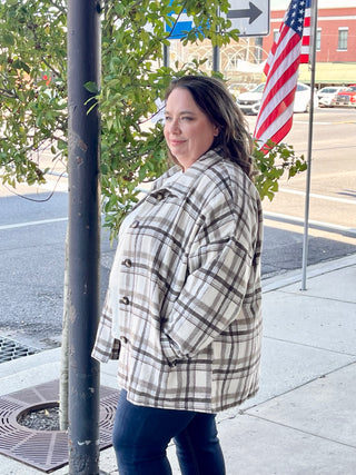 Woman standing in front of black pole wearing a light mocha jacket