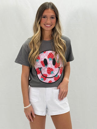 A person wearing a gray Strawberry Smiley T-Shirt paired with white shorts.