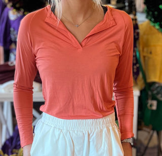 A person wearing a coral orange long-sleeved top and white bottoms