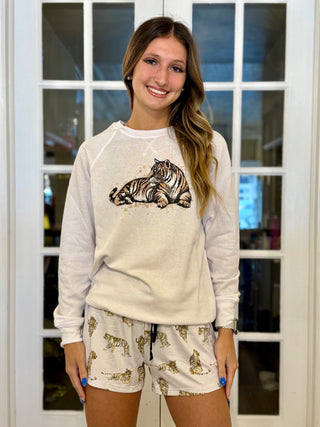 Woman wearing a white sweatshirt with a tiger design and matching shorts in front of a glass door.