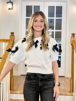 woman with white cropped short sleeve sweater with black bows