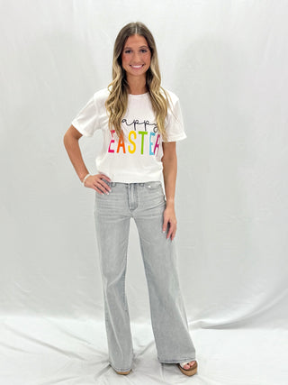 A person wearing high-rise full inseam jeans in a dove gray color, standing against a white background.