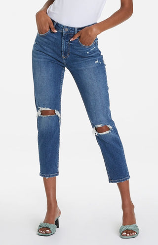 A pair of blue ripped jeans with a faded and distressed design, displayed on a model without showing the upper part of the body.