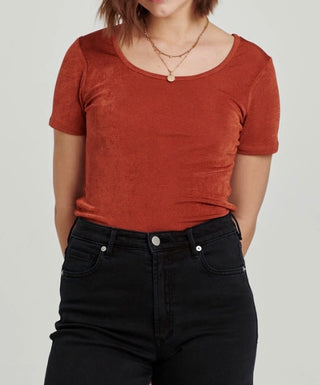 Woman wearing a burnt orange top paired with black jeans
