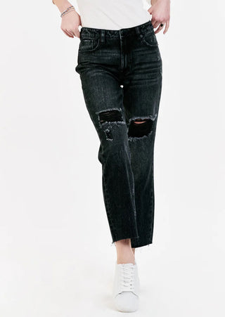 A woman holding the waist of the black distress denim jeans.