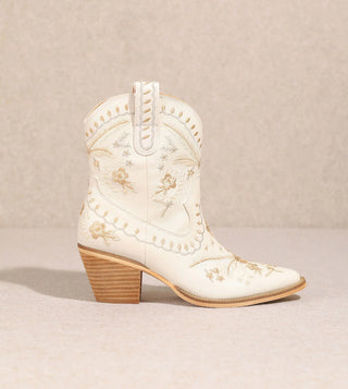 A white, synthetic, casual style boot with a round toe and a low heel, decorated with small floral patterns and ivory accents.