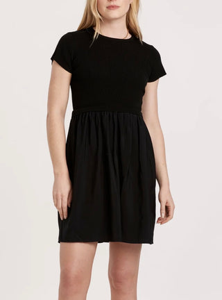 Black dress worn by a person on a light pink background