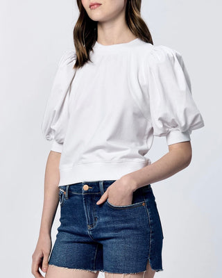 Person wearing a white blouse and blue shorts on a plain background