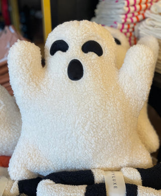 A beige plush pillow resembling a ghost with a smiling face, presented on a flat surface.
