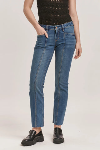 Person wearing blue jeans and black shoes on a white background
