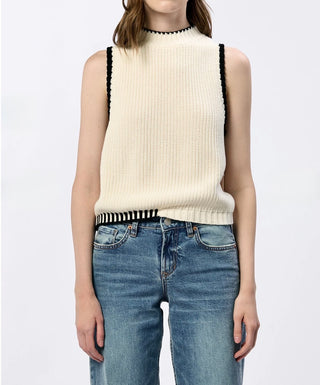 Woman wearing a cream sweater with black accents, paired with blue jeans