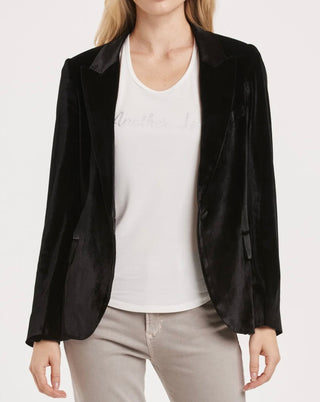 Woman wearing a black velvet blazer open with white shirt underneath