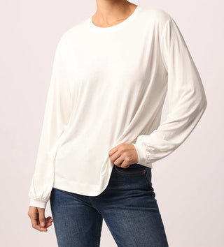 Woman wearing a white long sleeve top with blue jeans