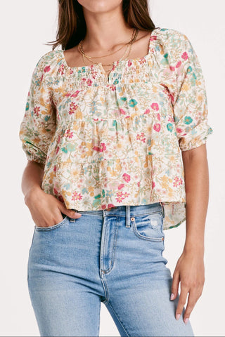 Woman wearing a floral blouse and blue jeans on a white background