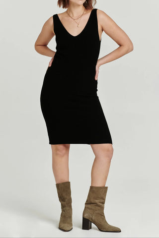 Person wearing a black sleeveless dress with brown knee-high boots on a white background