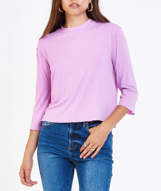 Person wearing a light purple long-sleeve shirt and blue jeans on a white background