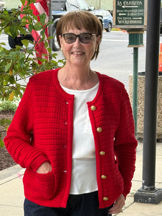 Woman wearing a red cardigan with gold buttons outdoors