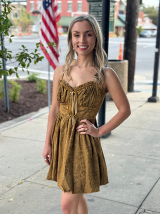 Woman in a olive dress standing outdoors with a blurred background
