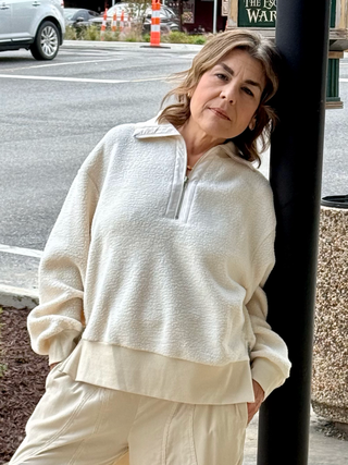 Woman wearing a beige outfit standing on a street corner