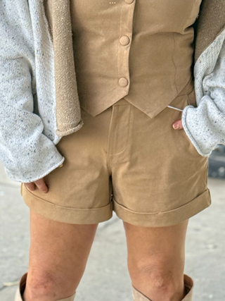 Person wearing a beige vest and shorts with a blurred background