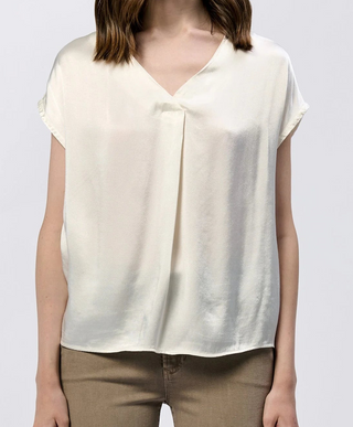 Person wearing a white sleeveless top and brown pants on a plain background