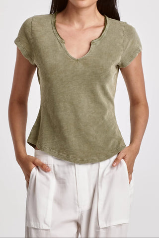Woman wearing a green top and white pants on a plain background