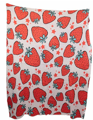 An oversized blanket with a colorful pattern of strawberries and stars on a beige background.