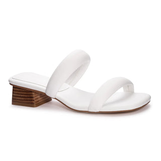 A white sandal with a smooth sole and a wooden heel, with the white puff straps.