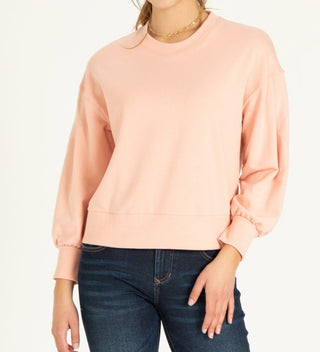 Dusty pink colored sweatshirt paired with dark denim jeans