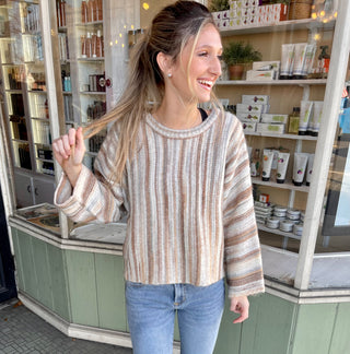 Woman wearing a multicolor brown striped sweater with blue denim jeans