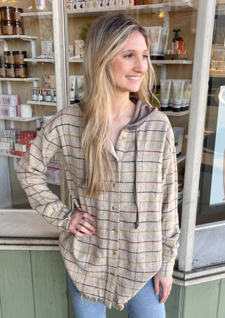 Woman wearing a khaki color plaid shacket with a hoodie attached