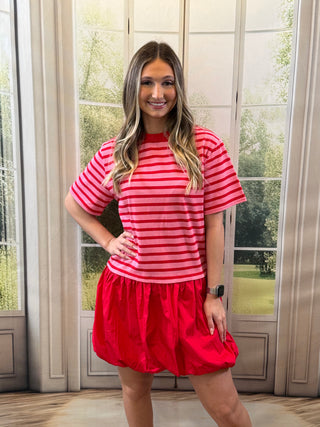 A woman wearing a pink and red striped dress with a red bubble ￼silhouette￼ design at the bottom