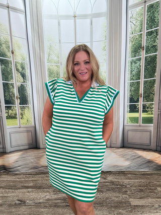 Woman wearing a green and white striped dress standing in front of a glass door.