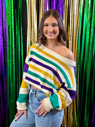 Woman wearing a colorful striped sweater in front of a vibrant curtain.