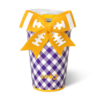A purple and white gingham patterned tumbler cup with a yellow band at the rim, decorated with a large yellow football-shaped bow featuring white laces. The word 'swag' is printed in yellow near the bottom.