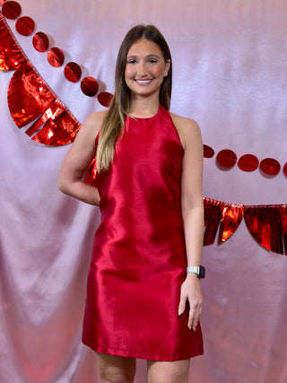 Woman in a red dress standing against a decorative red and white background
