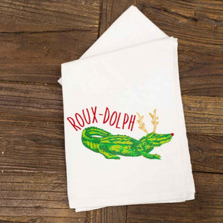 White towel with a green crocodile and red text on a wooden surface