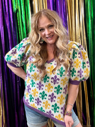 Woman wearing a colorful patterned sweater in front of a vibrant curtain.