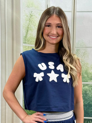 Woman wearing a navy blue sleeveless top with 'USA' and star graphics, standing indoors.