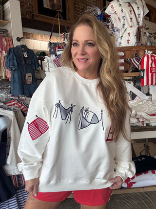 Woman wearing a white sweatshirt with graphic designs in a store setting