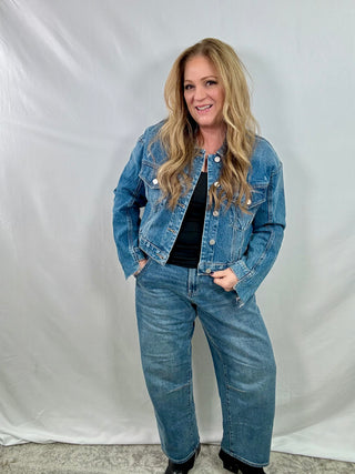 Woman wearing a blue denim jacket and jeans against a white background
