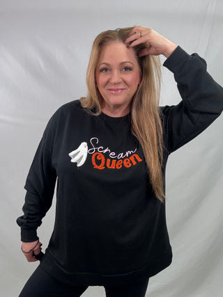 Woman wearing a black sweatshirt with 'Scream Queen' text and graphic, posing against a plain background.