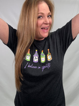 Woman wearing a black t-shirt with colorful bottle graphics and text on a plain background