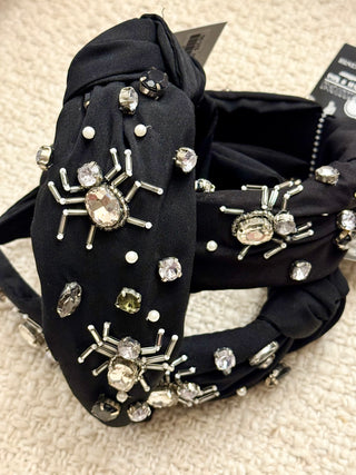 Black headband with spider embellishments on a textured surface