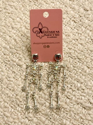 Skeleton design earrings on a Xpressions branded card against a textured beige background