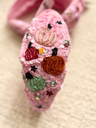 Decorative pink headband with colorful pumpkins and sequins on a beige background