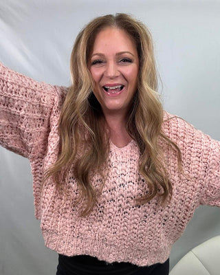 Woman wearing a pink crotchet sweater smiling 
